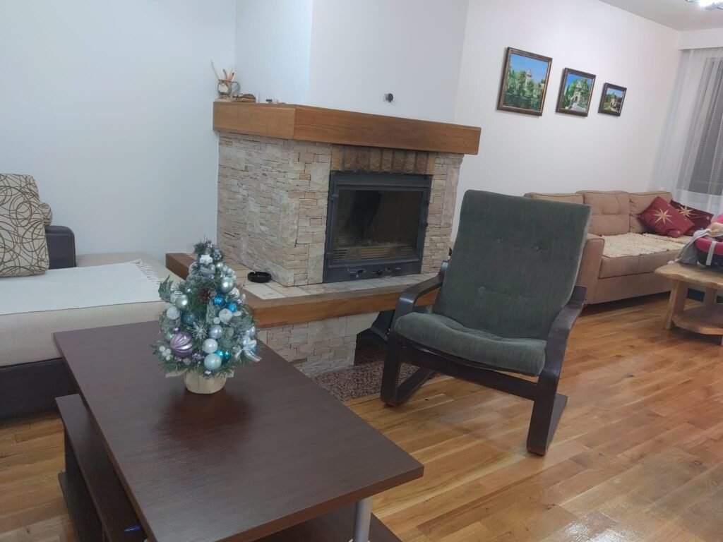 Kamin, fotelja i stočić od masivnog drveta – Peko apartman Jahorina